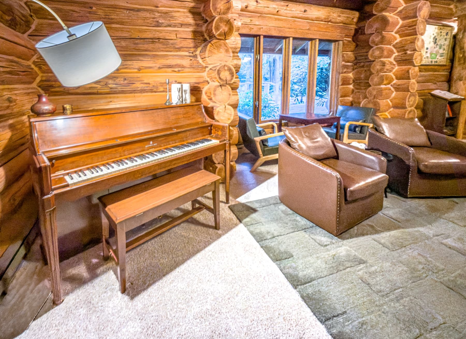 Great room — Steinway piano, log walls, leather seating