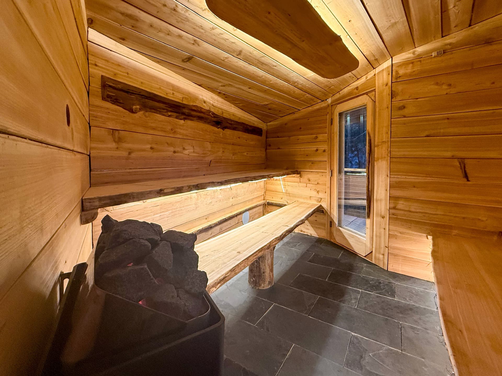 Treehouse sauna interior — cedar, slate, live-edge benches
